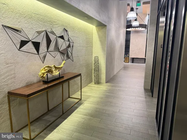 a hallway with wooden floor stairs and a chandelier