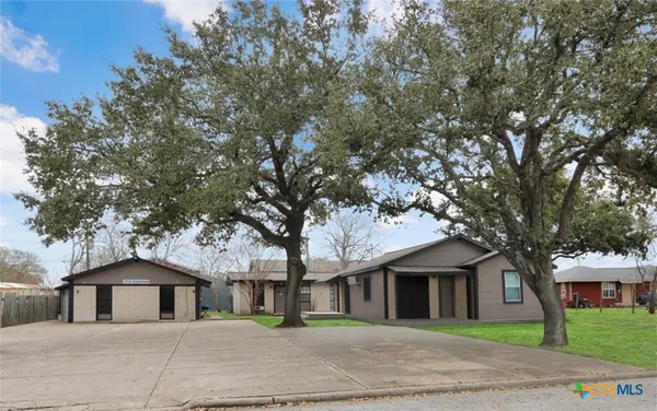 a front view of a house with a garden and trees