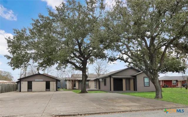 a front view of a house with a garden and trees