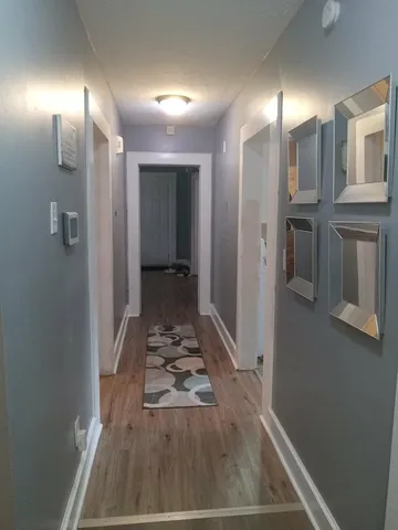 a view of a hallway with wooden floor and a living room