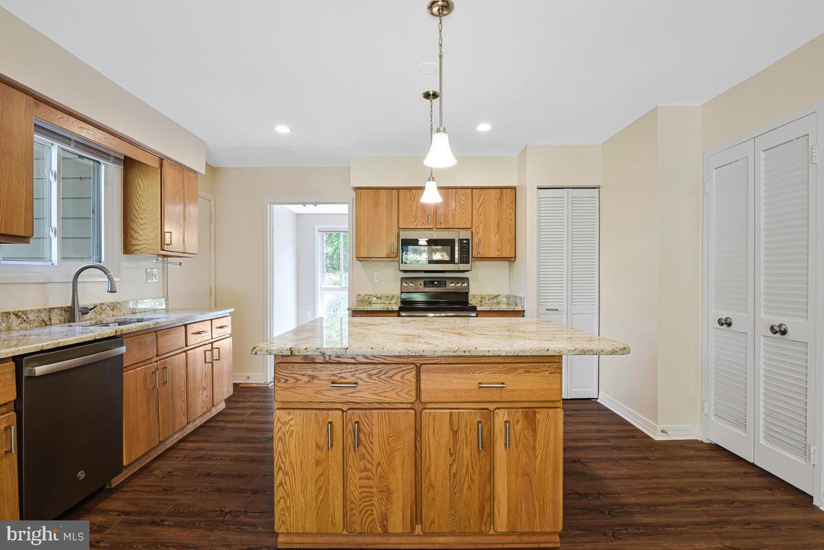 11814 Blue Spruce Road Reston, VA 20191 - Photo 11 of 56 a kitchen with kitchen island granite countertop wooden floors white cabinets and stainless steel appliances
