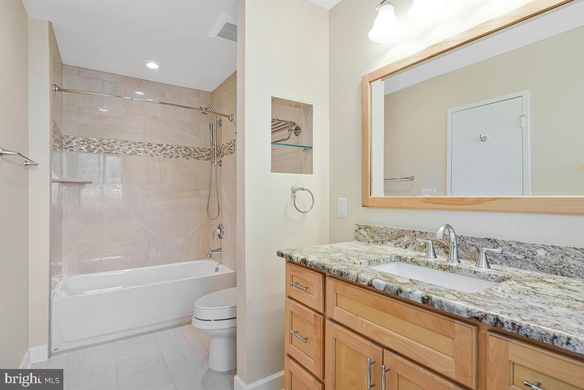 11814 Blue Spruce Road Reston, VA 20191 - Photo 30 of 56 a bathroom with a granite countertop sink a toilet and a large mirror