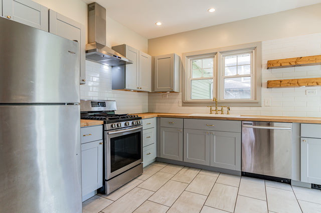 1616 West Church Street Champaign, IL 61821 - Photo 11 of 32 a kitchen with stainless steel appliances granite countertop a refrigerator a sink a stove and white cabinets