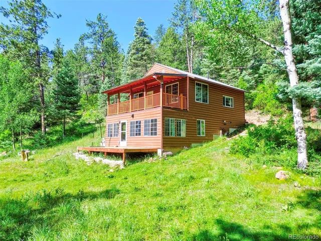 a brick house with a small yard plants and large trees