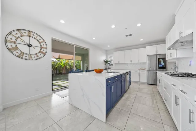a large kitchen with stainless steel appliances granite countertop a large counter top a stove a microwave oven and a sink with granite countertops