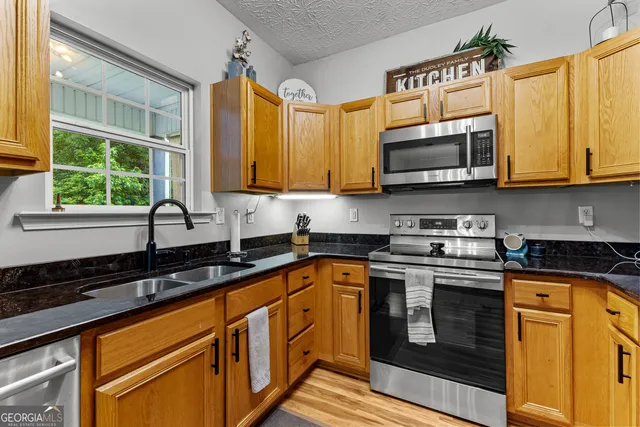 a kitchen with stainless steel appliances granite countertop a sink a stove and cabinets