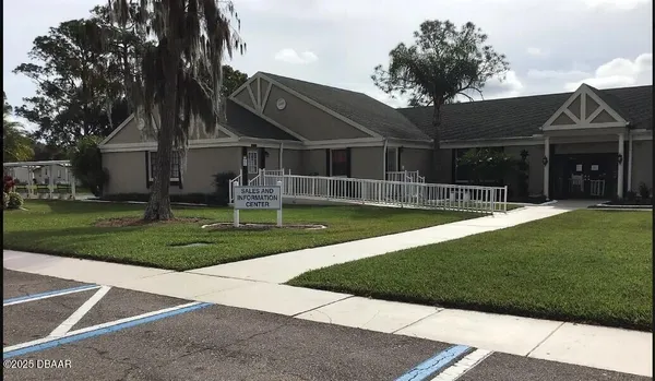 a view of a house with a yard potted plants and a table