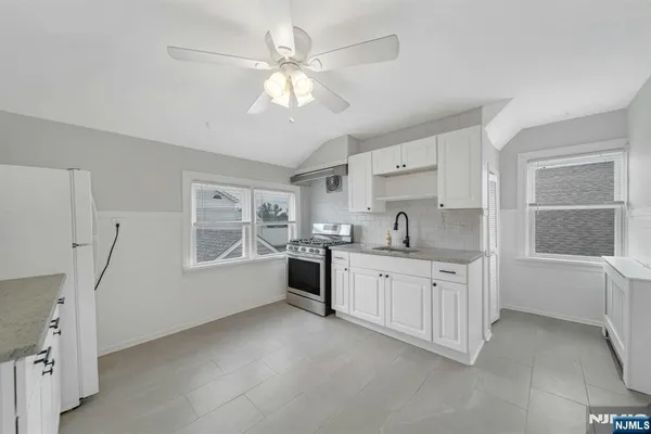 a large white kitchen with granite countertop a sink cabinets and a large window