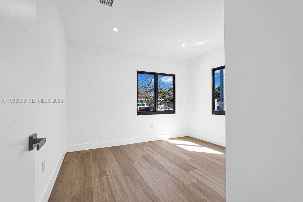 3040 Northwest 13th Avenue Miami, FL 33142 - Photo 12 of 46 a view of an empty room with wooden floor and a window