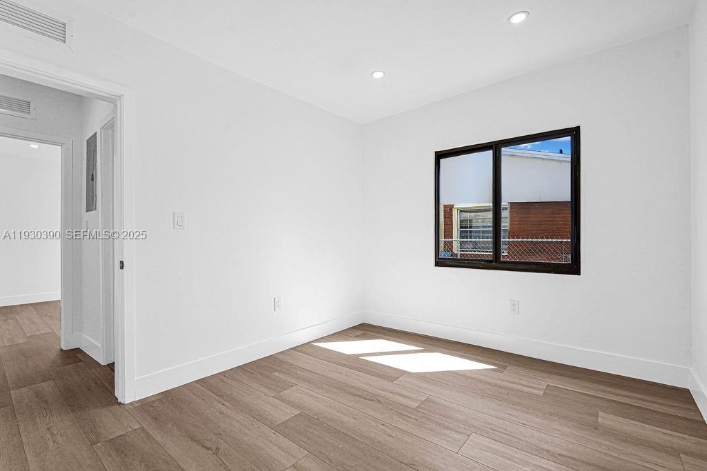 3040 Northwest 13th Avenue Miami, FL 33142 - Photo 6 of 46 an empty room with wooden floor and windows