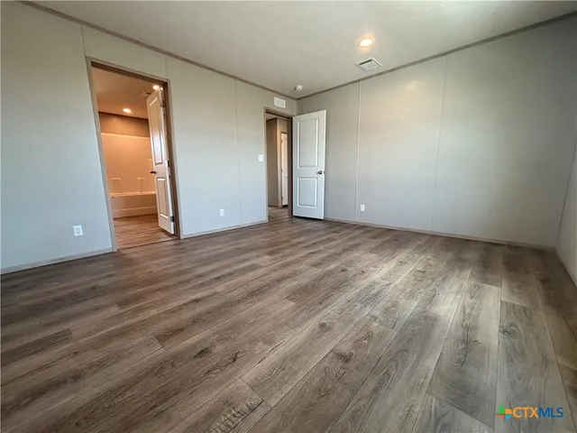 a view of an empty room with wooden floor and closet