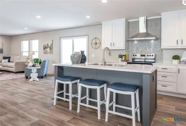 a kitchen with granite countertop a sink cabinets and wooden floor