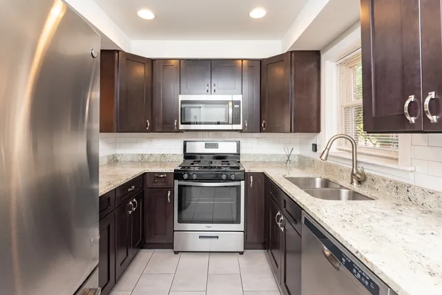 a kitchen with stainless steel appliances granite countertop a sink stove and refrigerator
