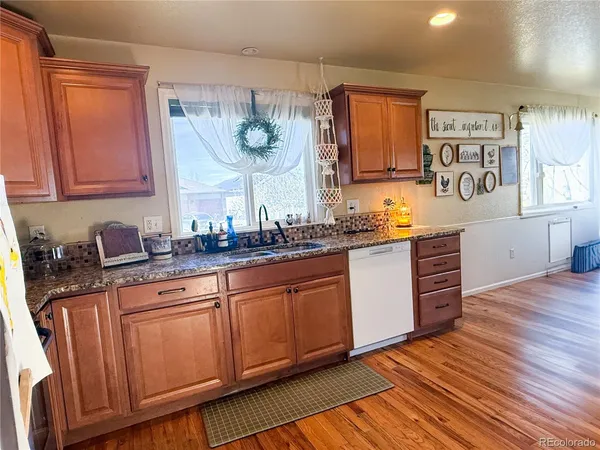 a kitchen with stainless steel appliances granite countertop wooden cabinets a sink and dishwasher with wooden floor