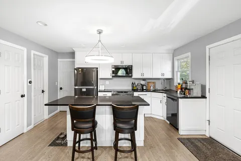 a kitchen with kitchen island granite countertop a sink stove and white cabinets