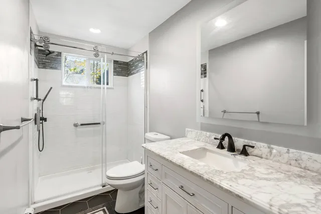 a bathroom with a granite countertop sink toilet and shower
