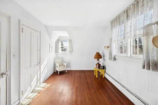 a bedroom with wooden floor and a window