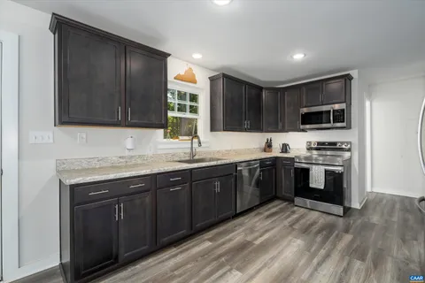 a kitchen with granite countertop wooden cabinets a stove top oven and stainless steel appliances