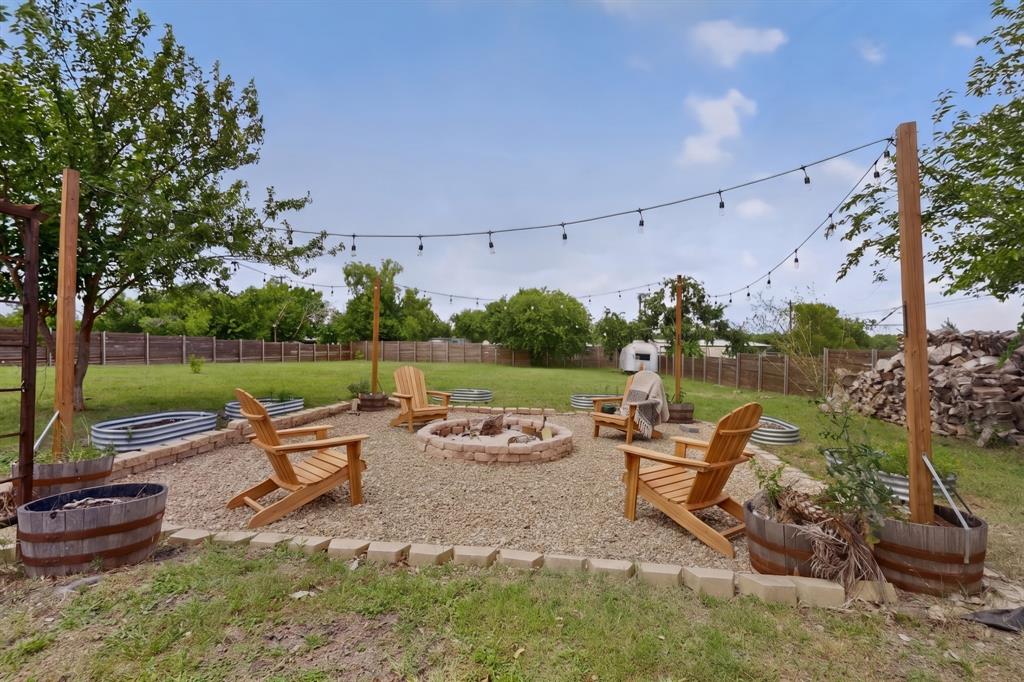 304 East County Line Road Royse City, TX 75189 - Photo 1 of 38 Expansive backyard featuring a central fire pit with stone surround, string lighting, and a gravel seating area bordered by stone pavers