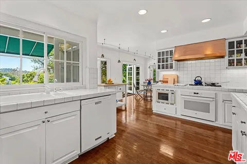 a kitchen with stainless steel appliances white cabinets and wooden floors