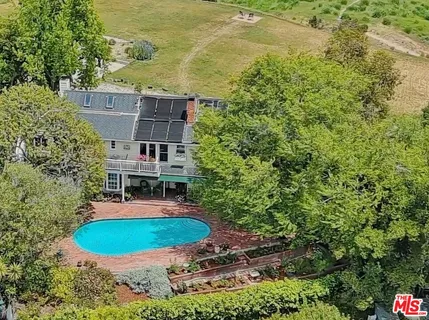 a view of a white house with a big yard and large trees