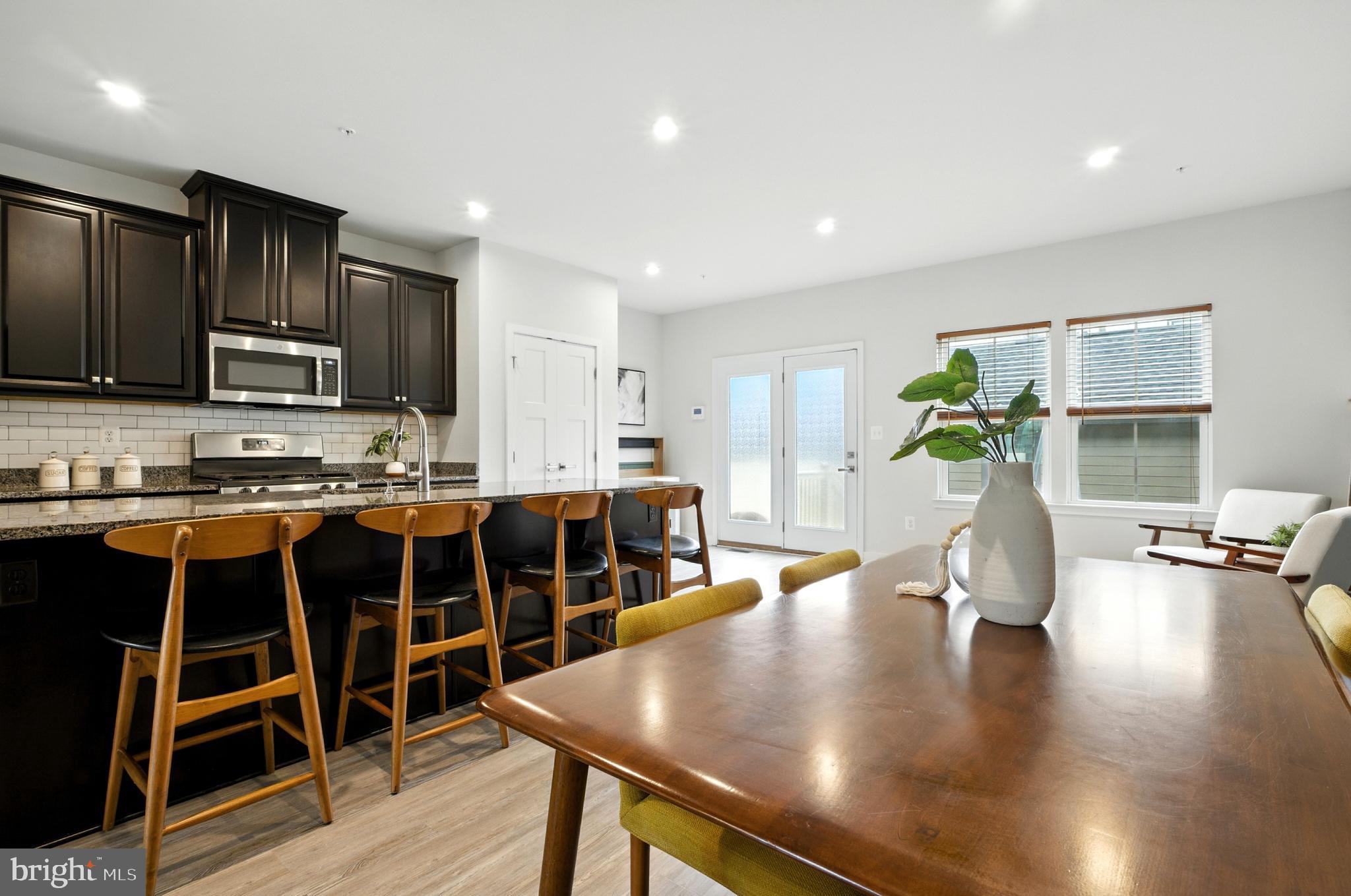 6412 Dalston Street Middle River, MD 21220 - Photo 19 of 53 a kitchen with stainless steel appliances granite countertop a stove top oven a dining table and chairs with wooden floor