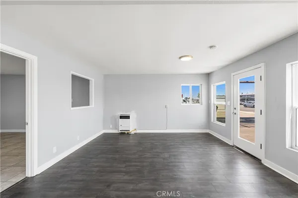 a view of an empty room with window and wooden floor