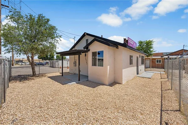 a front view of a house with a dirt yard and a large tree