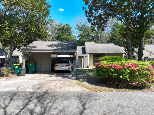 a view of a house with potted plants and a large tree