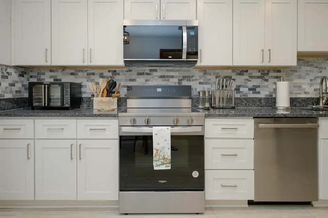 a kitchen with granite countertop white cabinets and stainless steel appliances