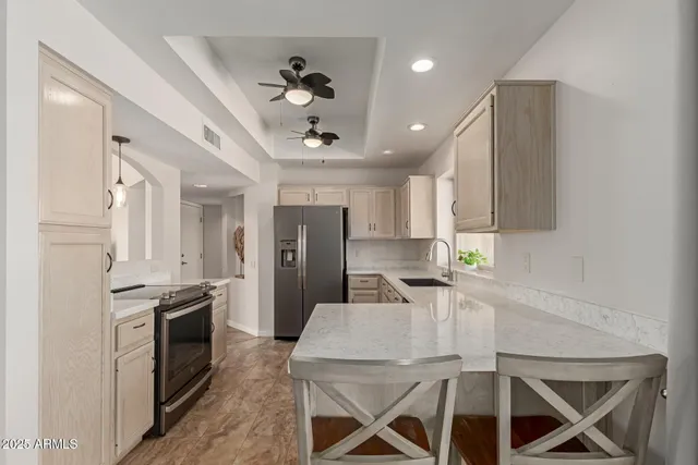 a kitchen with stainless steel appliances kitchen island granite countertop a refrigerator a stove a sink a dining table and chairs with wooden floor