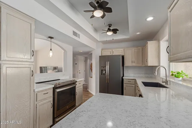 a kitchen with stainless steel appliances kitchen island granite countertop a refrigerator a sink dishwasher a stove and a refrigerator with wooden floor