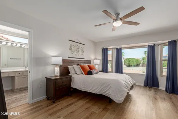 a bedroom with a large bed a large window with wooden floor