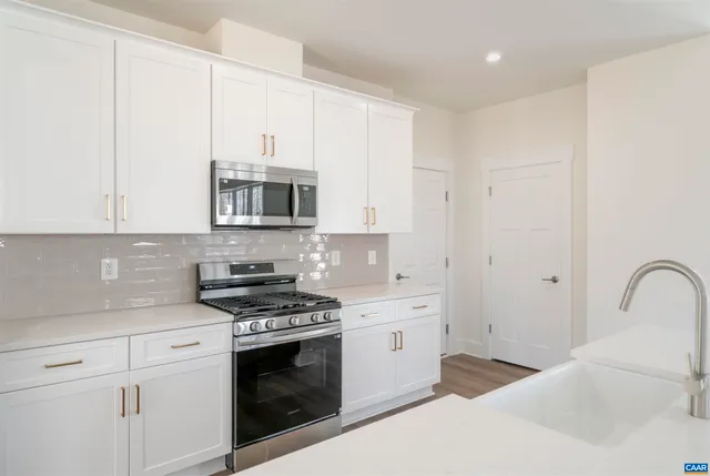 a kitchen with granite countertop white cabinets and stainless steel appliances