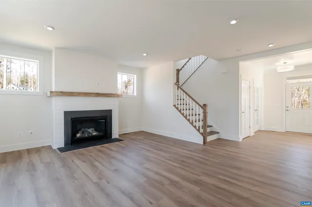 a view of an empty room with wooden floor fireplace and a window