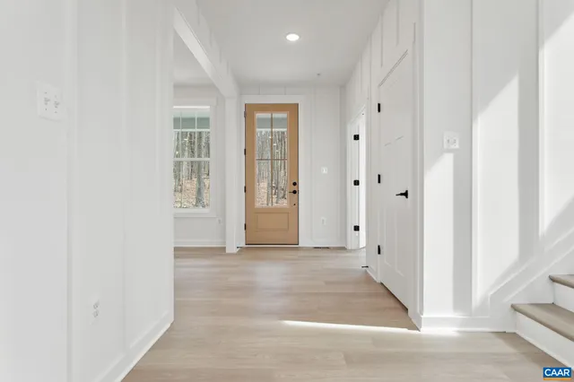 an entryway space with wooden floor and bathroom view