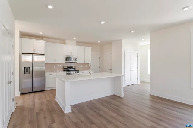 a large kitchen with stainless steel appliances a sink and a refrigerator