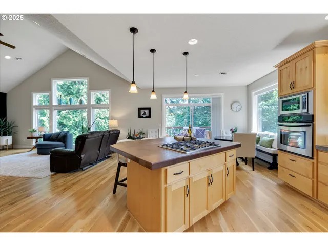 a kitchen with stainless steel appliances granite countertop a stove top oven a dining table with wooden floor