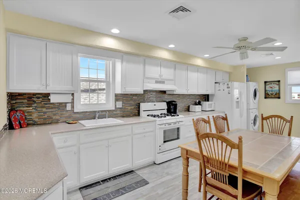 a kitchen that has a lot of cabinets in it with granite countertop a sink a stove a dining table and chairs