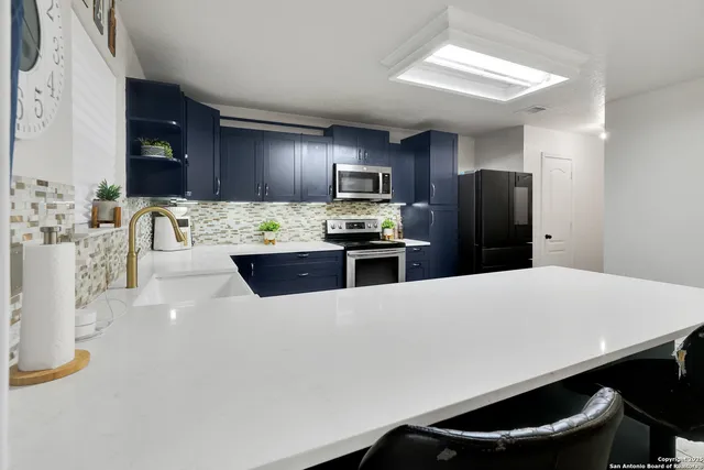 a kitchen with stainless steel appliances a refrigerator and a stove top oven