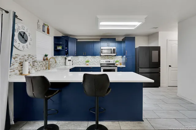 a kitchen with stainless steel appliances granite countertop a refrigerator a stove a sink and chairs