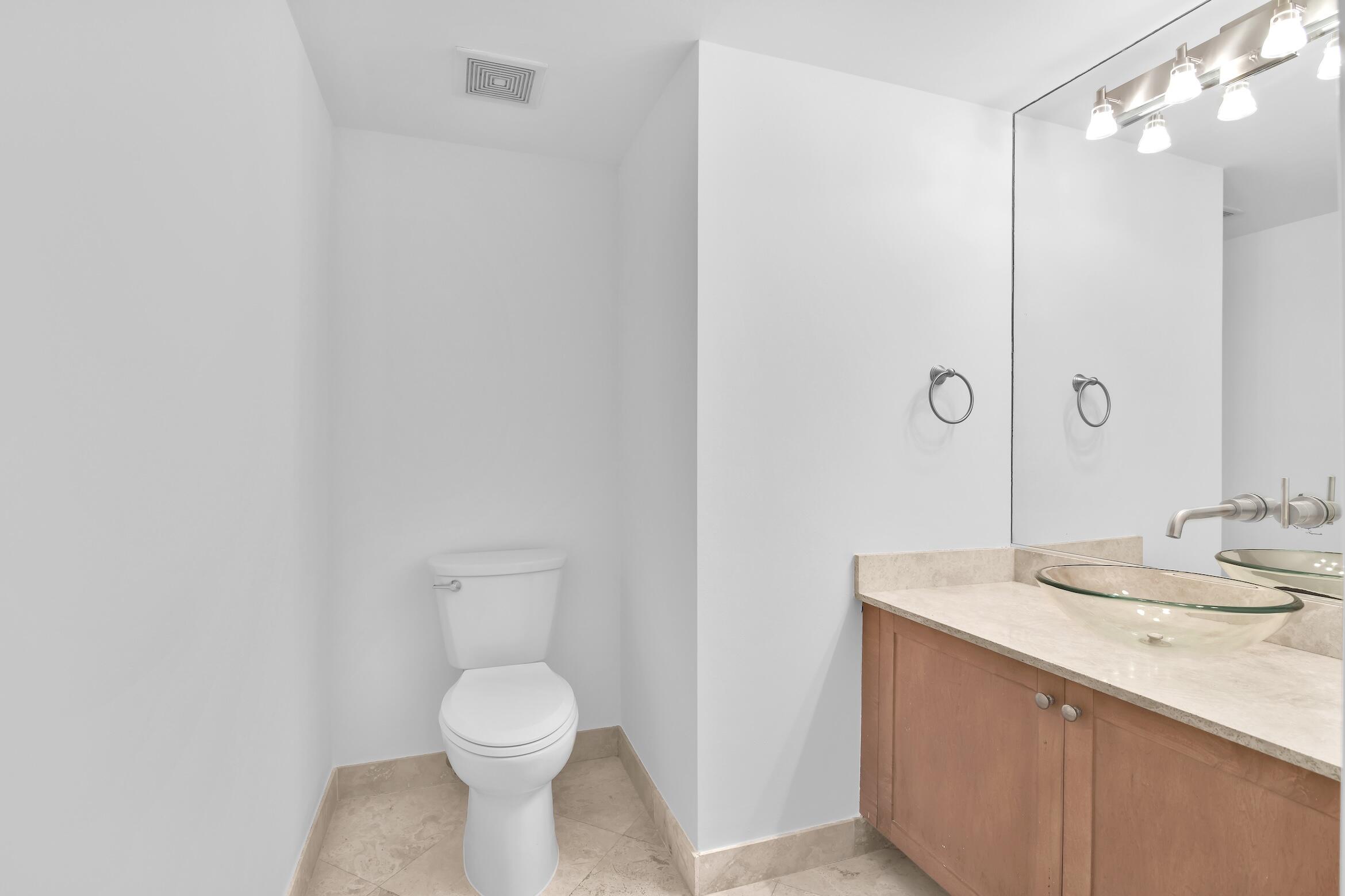 99 Southeast Mizner Boulevard, Unit PH 40 Boca Raton, FL 33432 - Photo 18 of 48 a bathroom with a toilet sink and mirror