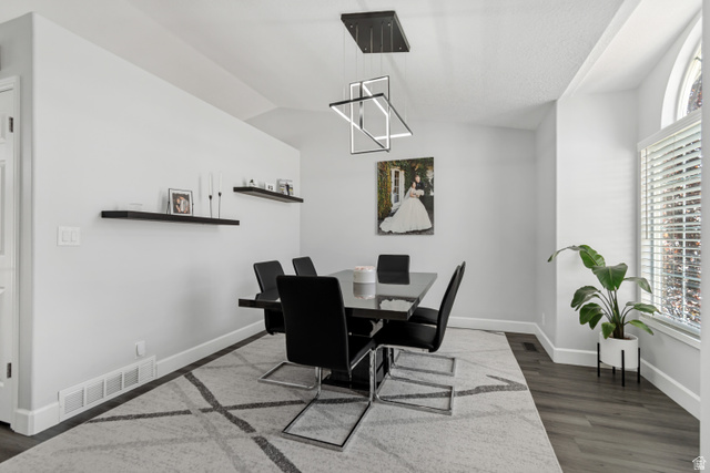 4752 South 4075th Street West Roy, UT 84067 - Photo 3 of 28 Dining area featuring a contemporary linear chandelier, dark wood-finish flooring, a large arched window with blinds, and white baseboards