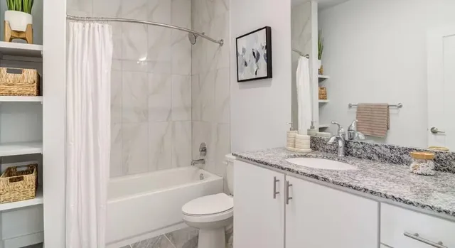 a bathroom with a granite countertop sink mirror toilet and bathtub