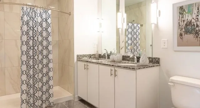 a bathroom with a granite countertop sink and a toilet