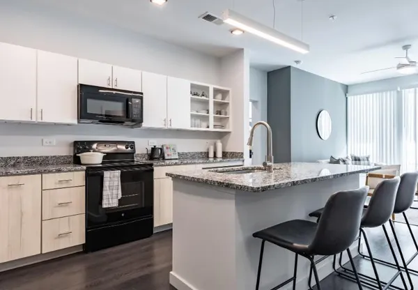 a kitchen with stainless steel appliances granite countertop a stove top oven a sink dishwasher and white cabinets with wooden floor