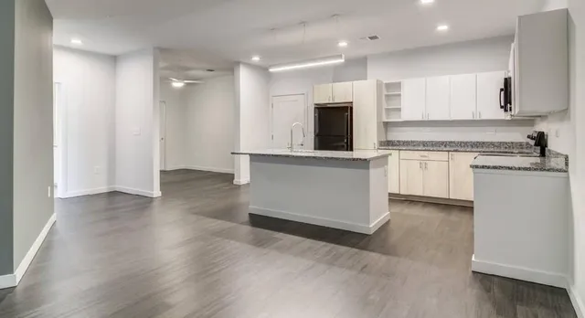 a kitchen with stainless steel appliances granite countertop a stove top oven a sink and white cabinets with wooden floor