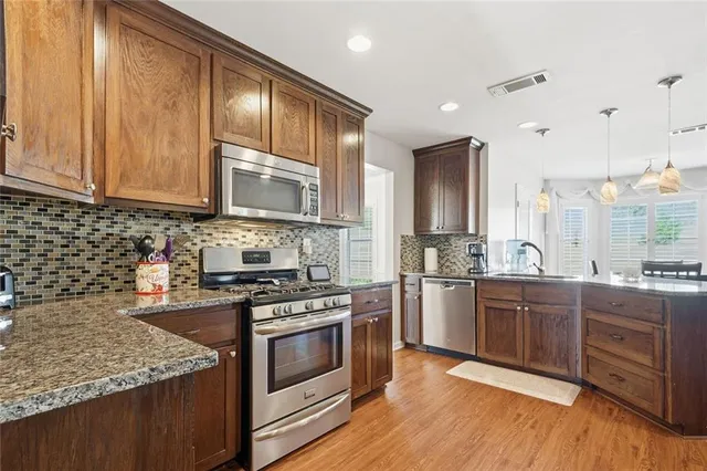 a kitchen with stainless steel appliances granite countertop wooden cabinets stove top oven and sink