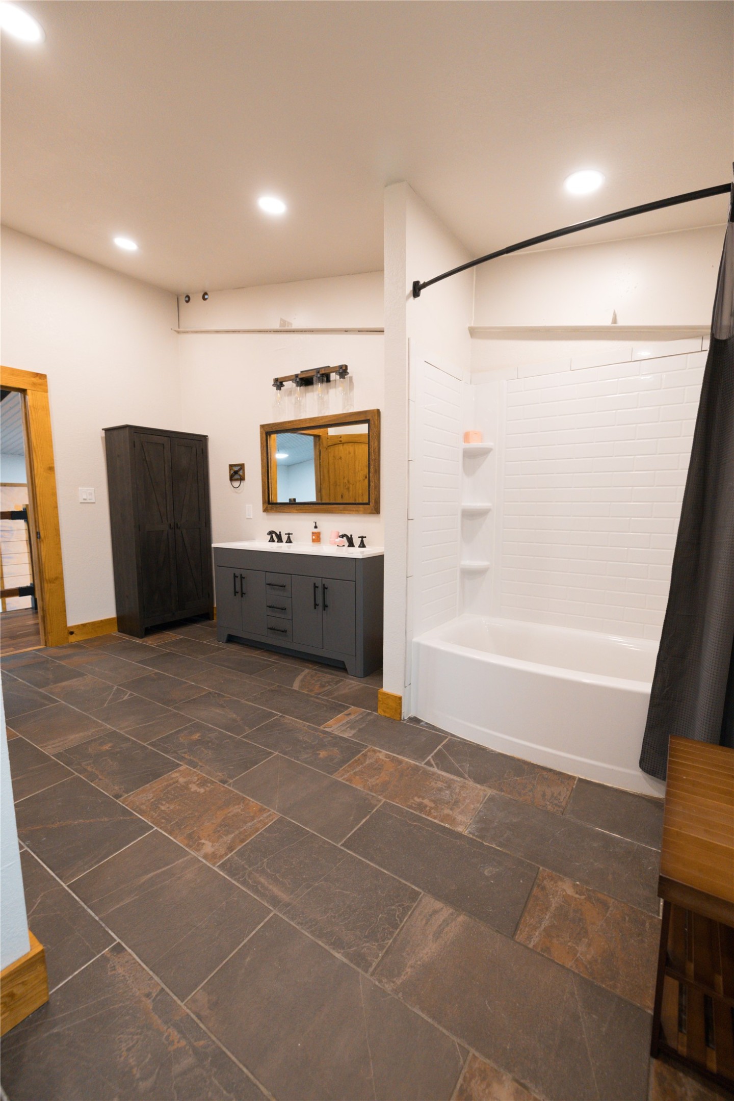 143 County Road Paige, TX 78659 - Photo 16 of 36 Upstairs Full bath featuring double vanity, shower / tub combo, recessed lighting, and stone tile flooring