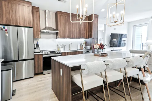 a kitchen with stainless steel appliances a refrigerator a stove a sink and chairs